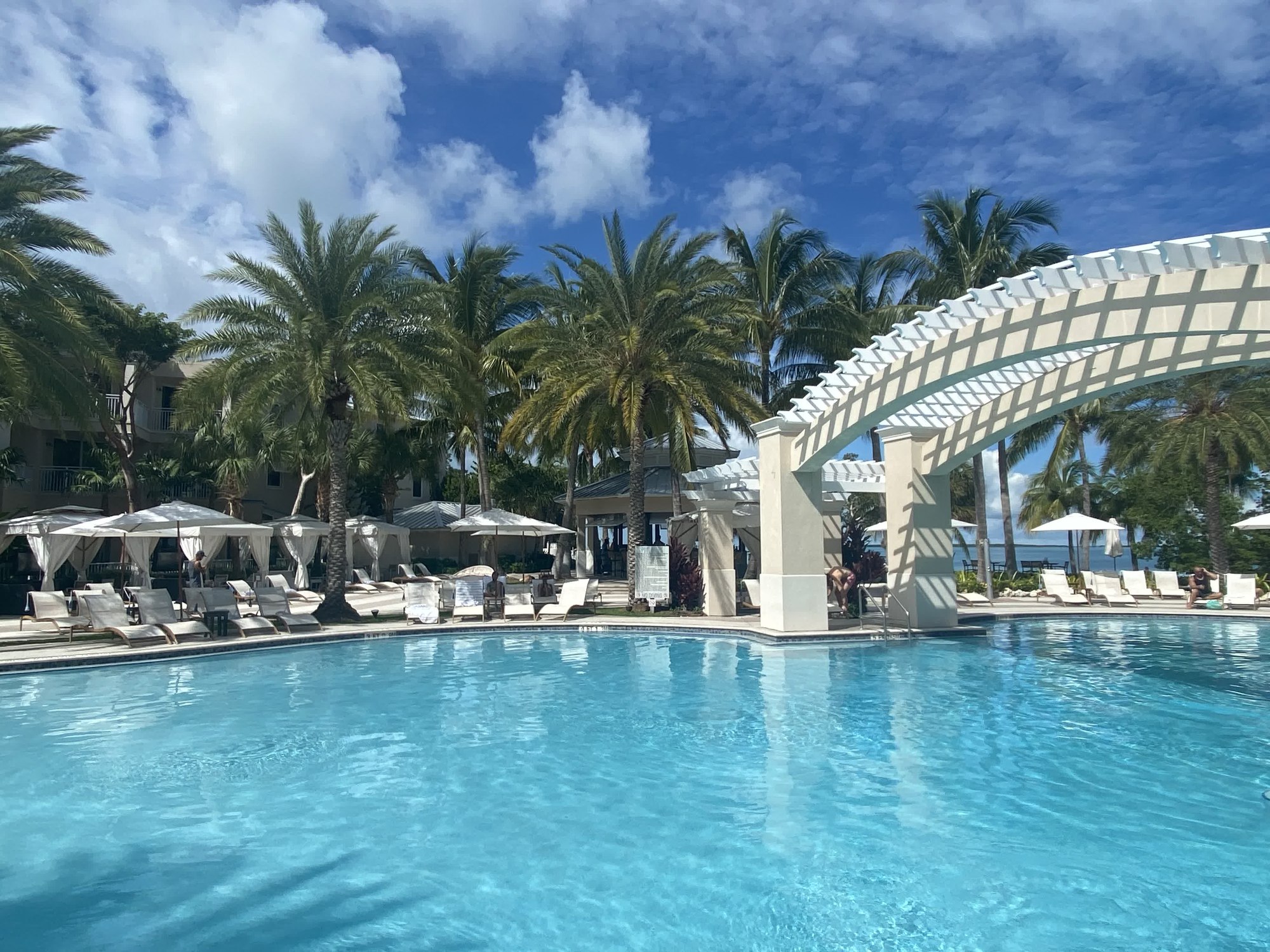 Resort pool with white arched pergola and palm trees