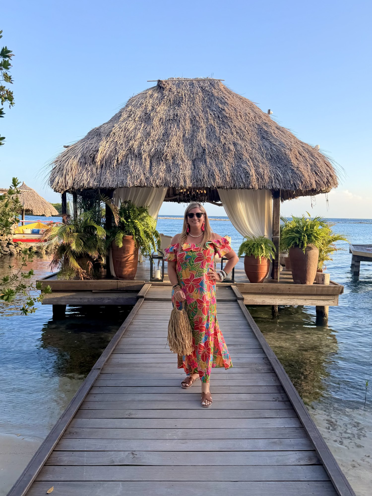 Woman in printed dress walking toward an overwater cabana