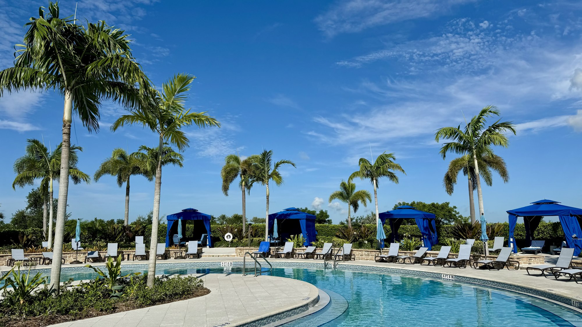 Resort pool lined with palm trees and blue cabanas