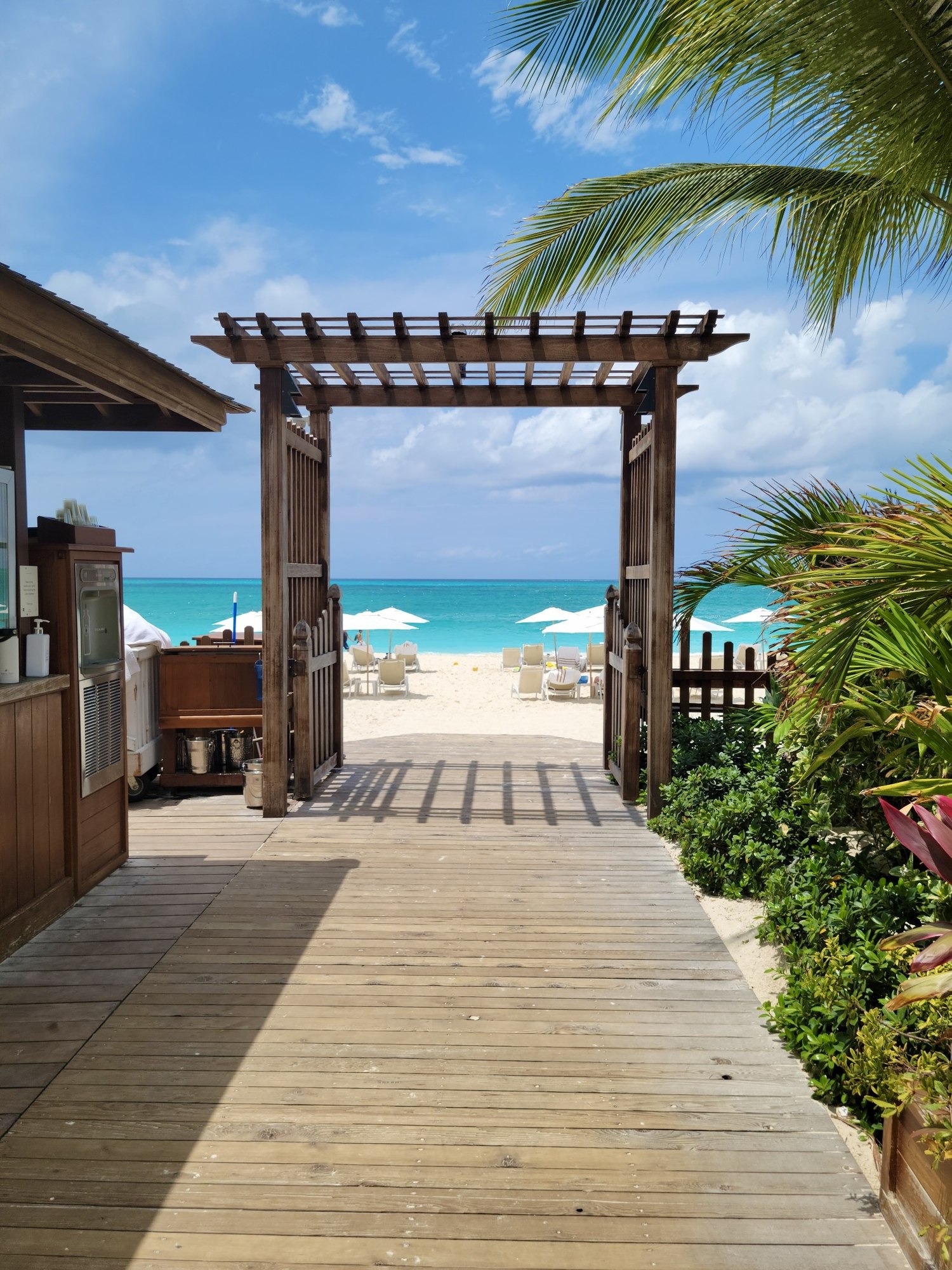 Wooden pergola archway framing a turquoise beach view